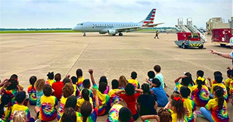 group of children watching a plane taxi on the ground
